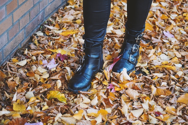 Person wearing black leather boots walking in the colorful leaves