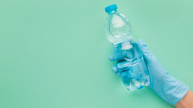 Person wearing gloves holding a plastic bottle