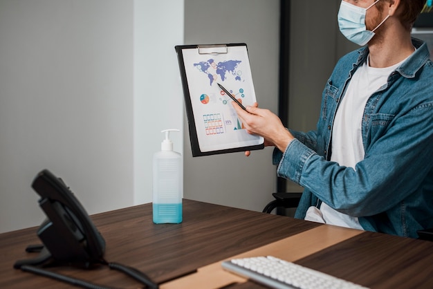 Foto gratuita persona che indossa una maschera medica e mostra un blocco per appunti