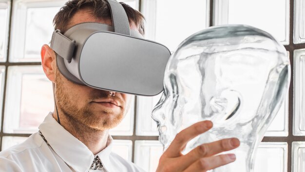 Person wearing virtual reality goggles holding a transparent mannequin