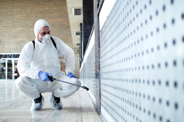 Free photo person in white chemical protection suit doing disinfection of public areas to stop spreading highly contagious corona virus