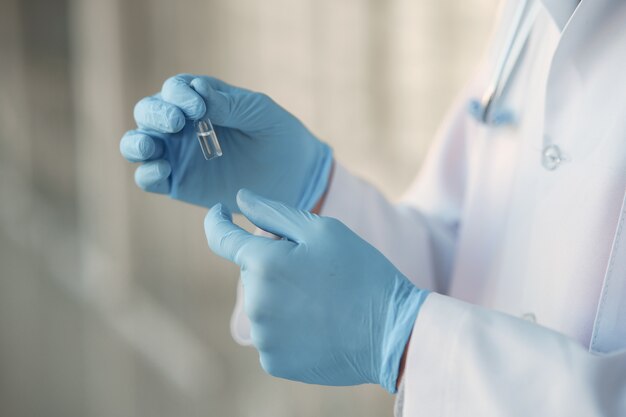 Person in a white uniform holding a ampoule in her hands