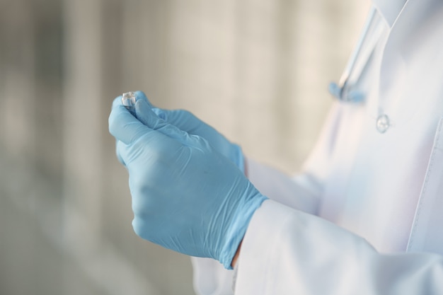 Free photo person in a white uniform holding a ampoule in her hands