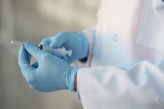 Person in a white uniform holding a syringe in her hands