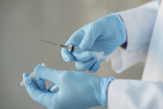 Person in a white uniform holding a syringe in her hands