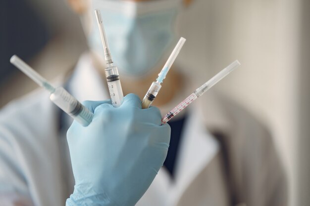 Person in a white uniform holding a syringe in her hands