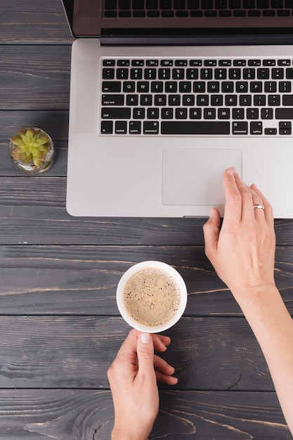 Person with coffee working on laptop 