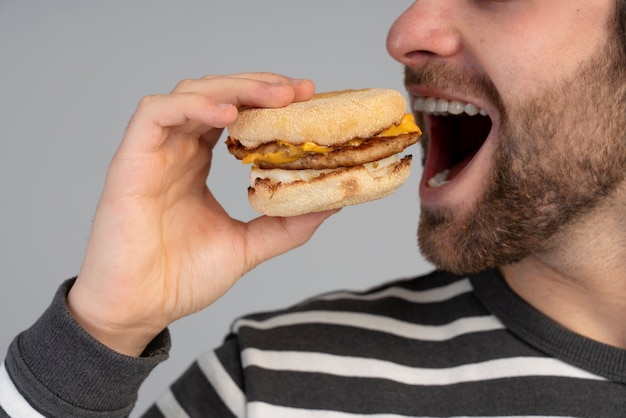 Бесплатное фото Человек с расстройством пищевого поведения пытается съесть фаст-фуд