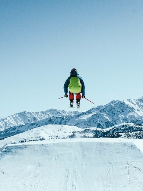 person with a green backpack skiing under the beautiful blue sky