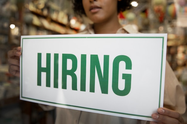 Person with hiring sign by the window