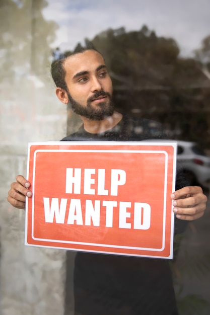 Free photo person with hiring sign by the window