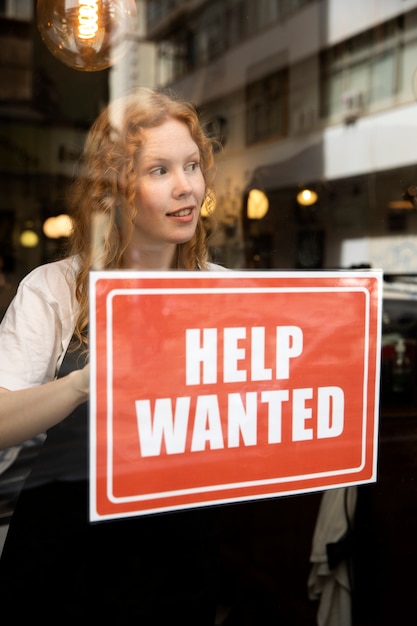 Person with hiring sign by the window