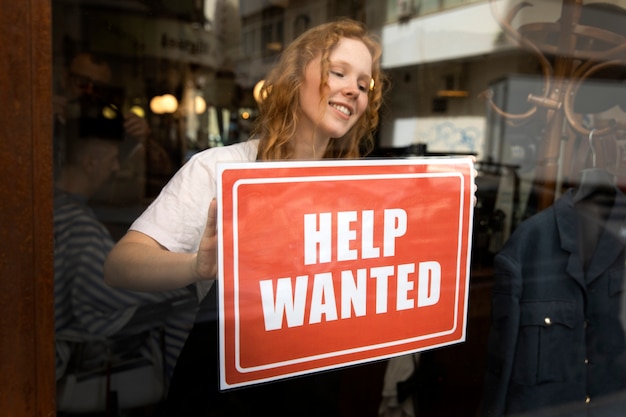 Person with hiring sign by the window