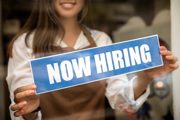 Person with hiring sign by the window