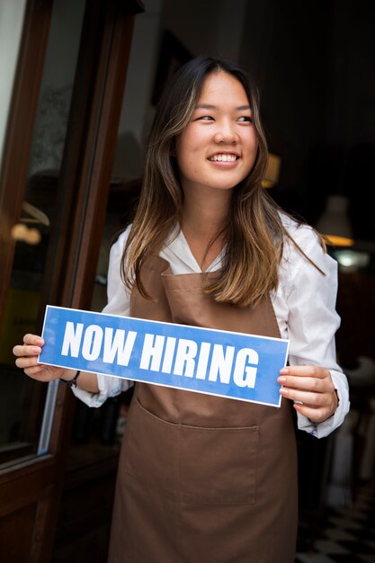 Person with hiring sign by the window