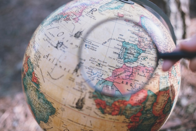 Person with magnifying glass looking at globe