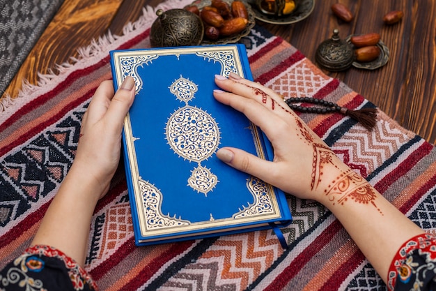 Foto gratuita persona con mehndi in possesso di corano vicino date frutta