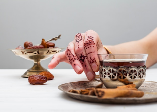 Person with mehndi holding tea cup on table