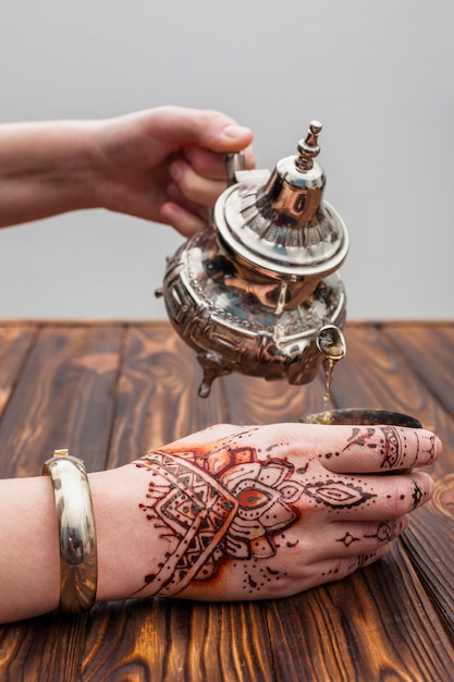 Foto gratuita persona con mehndi che versa il tè nella tazza