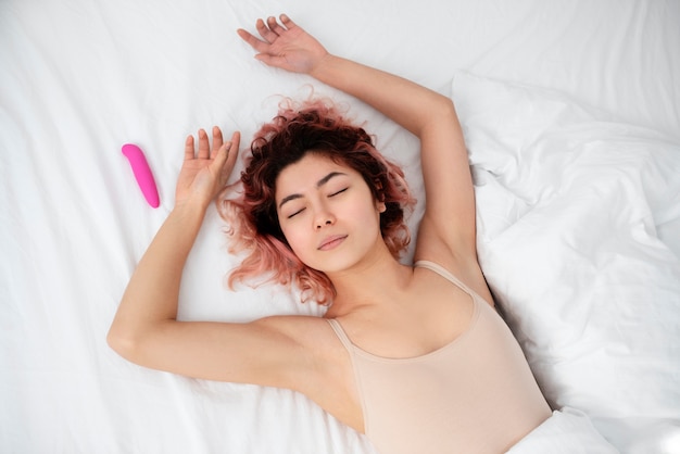 Foto gratuita persona con un giocattolo sessuale a letto