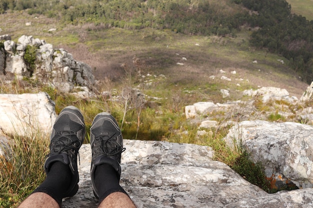 Free photo person with sports shoes sitting on a cliff and relaxing