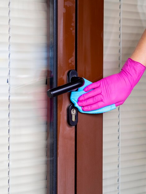 Person with surgical glove cleaning door handle