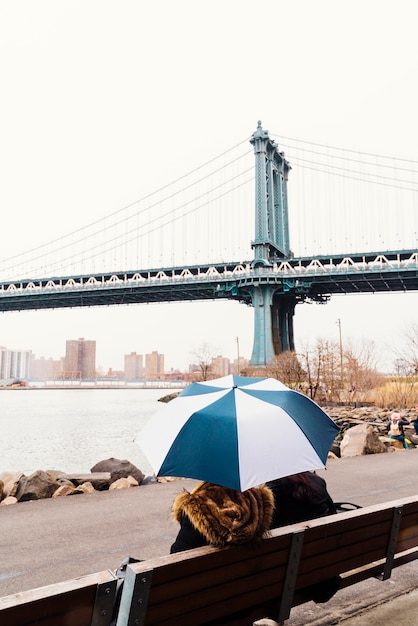 Бесплатное фото Человек с зонтиком, наслаждаясь видом на мост