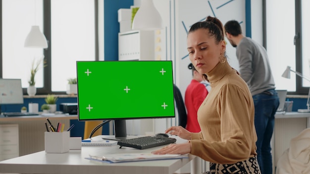 비즈니스 사무실에서 컴퓨터에서 녹색 화면으로 작업하는 사람. 빈 디스플레이에 격리된 모의 배경이 있는 크로마 키 템플릿을 보고 있는 여성입니다. 화면의 Chromakey 복사 공간