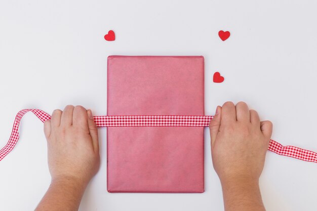 Person wrapping pink gift box on table 