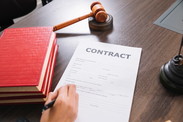 Person writing in document at table with books and gavel