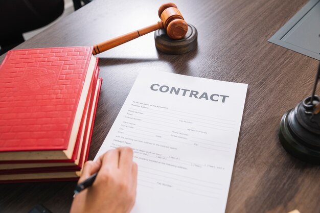 Person writing in document at table with books and gavel