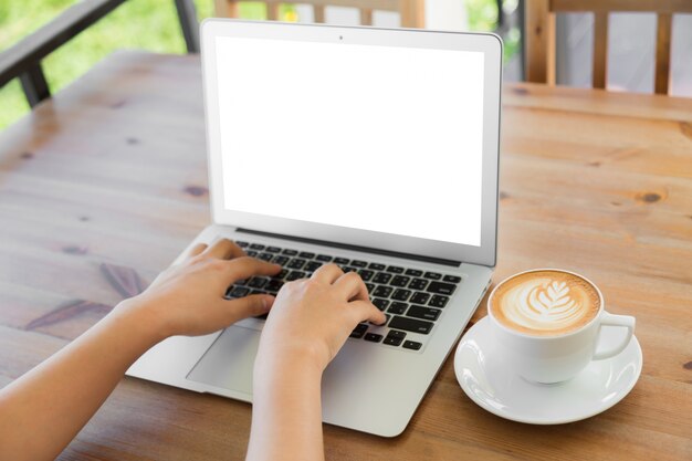 Person writing on a laptop with a coffee