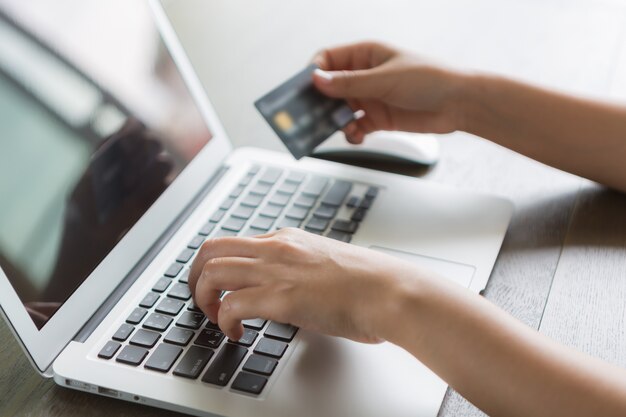 Person writing on a laptop with and a credit card