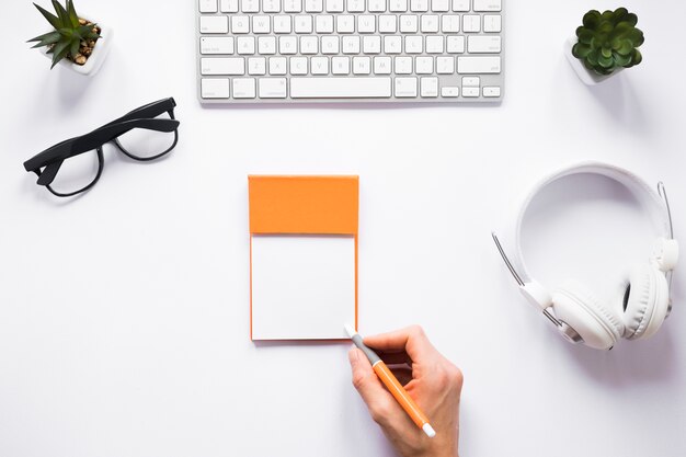 A person writing on sticky notes with pen on white workspace