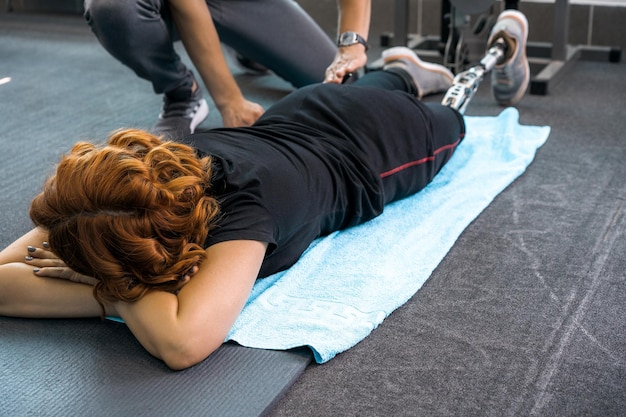 Personal trainer che assiste la donna con disabilità nel suo allenamento. centro di riabilitazione sportiva con fisioterapisti e pazienti che lavorano insieme per la guarigione.