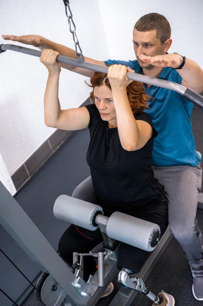 Personal trainer assisting woman with disabilities in her workout. Sports Rehab Centre with physiotherapists and patients working together towards healing.