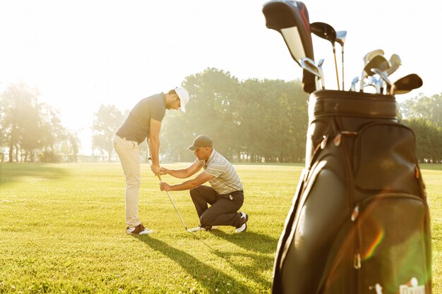Личный тренер дает урок молодому мужскому игроку в гольф
