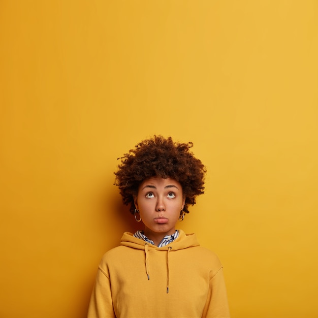 Pessimistic Afro American woman looks unhappily above