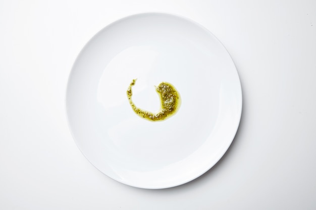 Pesto sause on white blank plate isolated top view