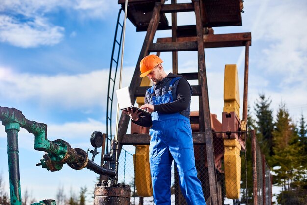 Petroleum engineer using laptop in oil field