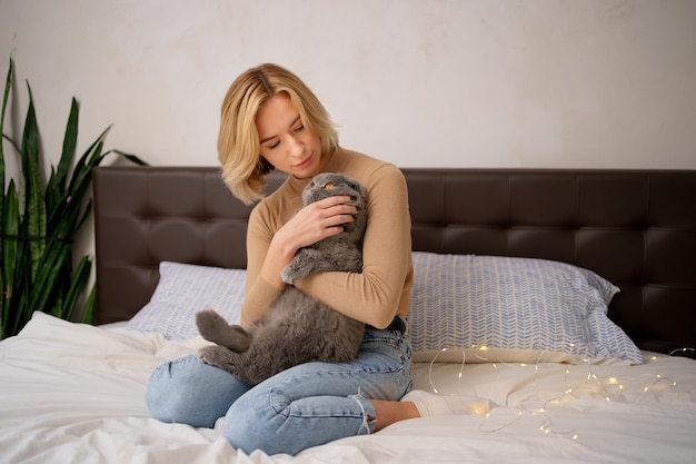 애완 동물, 아침, 편안함, 휴식과 사람들 개념-집에서 침대에서 고양이와 함께 행복 한 젊은 여자