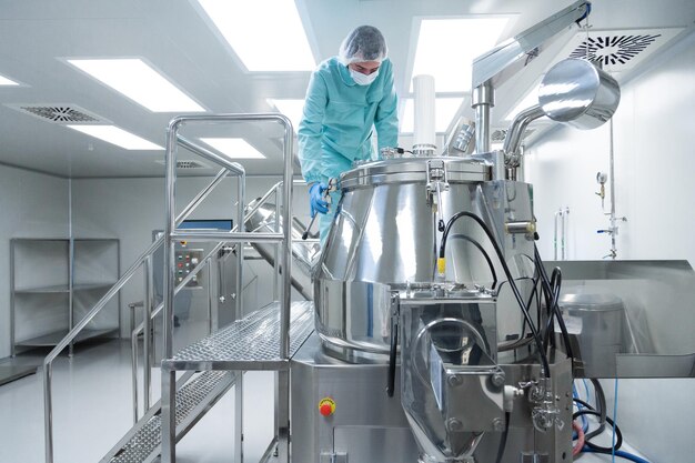 Pharmaceutical factory man worker in protective clothing operate production line in sterile working conditions