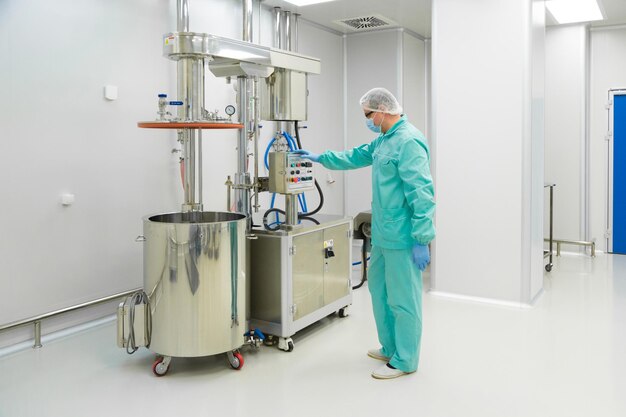 Pharmaceutical factory man worker in protective clothing working with control panel in sterile working conditions