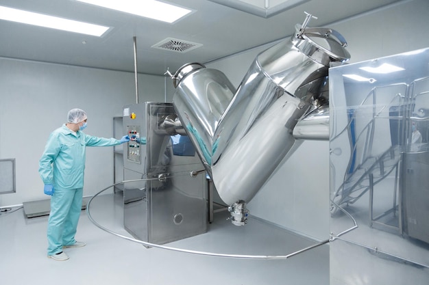 Pharmaceutical factory man worker in protective clothing working with control panel in sterile working conditions