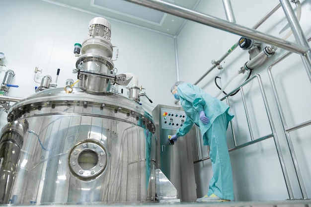 Free photo pharmaceutical factory woman worker in protective clothing operating production line in sterile environment