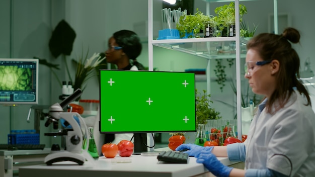 녹색 화면 크로마 키를 조롱하는 컴퓨터를 보고 있는 제약 연구원