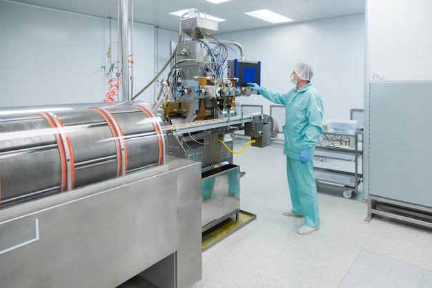 Pharmaceutical technician in sterile environment working with equipment at pharmacy industry