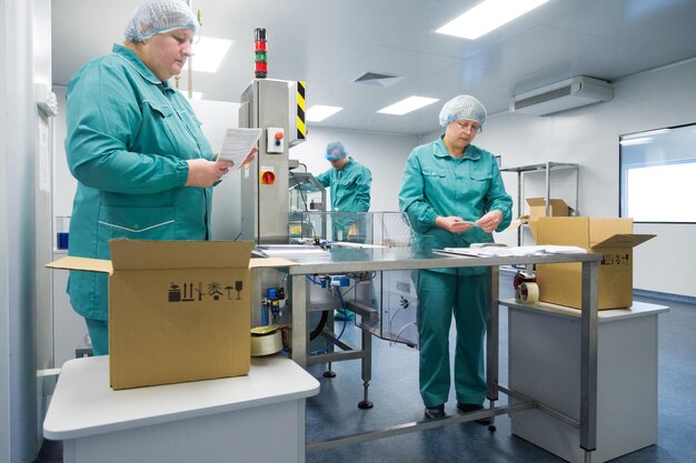 Pharmaceutical technicians work in sterile working conditions at pharmaceutical factory Scientists wearing protective clothing