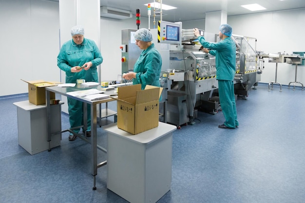 Pharmaceutical technicians work in sterile working conditions at pharmaceutical factory Scientists wearing protective clothing