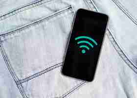 Foto gratuita telefono con il simbolo wifi sopra i jeans